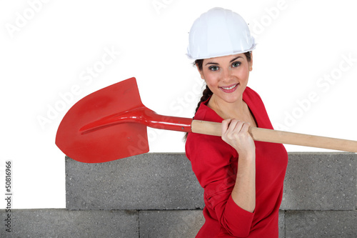 Photo: Woman stood by unfinished wall with spade Woman stood by unfinished wall with spade