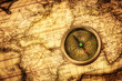 Vintage compass lies on an ancient world map.