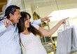 Happy couple pointing inside the store