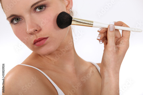 Photo: Woman applying blusher with brush Woman applying blusher with brush