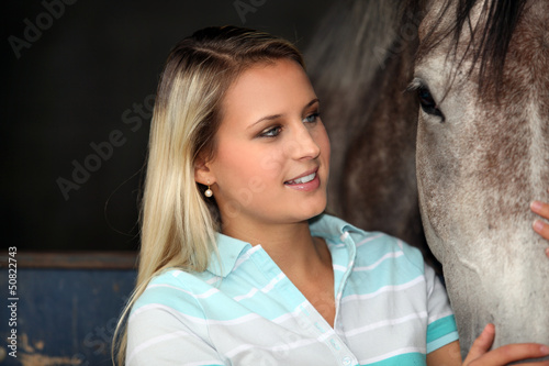 Photo: A young woman caressing a horse A young woman caressing a horse