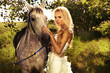 Beautiful blonde lady with posing with horse.