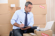 Man surrounded by cardboard boxes using a laptop
