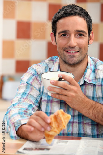 Photo: Man reading a newspaper at breakfast Man reading a newspaper at breakfast