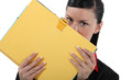 Businesswoman covering face with file