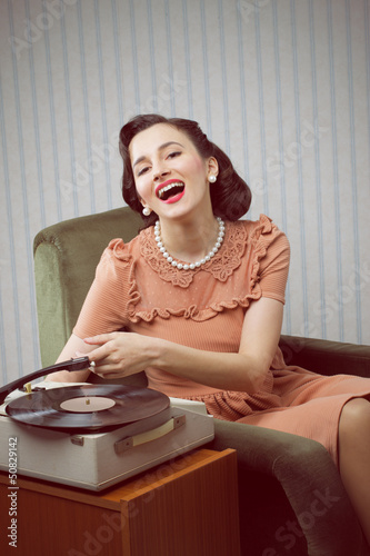 Photo: Young woman listening to music from a turntable Young woman listening to music from a turntable