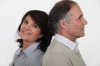 Married couple stood back to back in studio