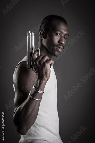Photo: Killer with gun close up over dark background. Killer with gun close up over dark background.