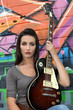 Woman with guitar in front of painted wall