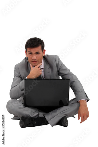 Photo: Pensive businessman sat on floor with laptop Pensive businessman sat on floor with laptop