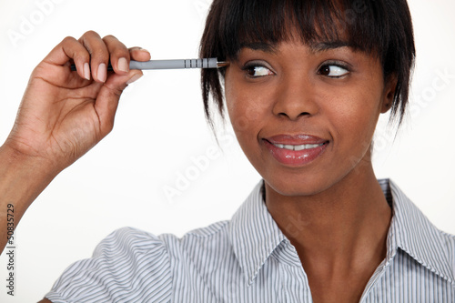 Photo: Women with pen pointing towards her temple Women with pen pointing towards her temple