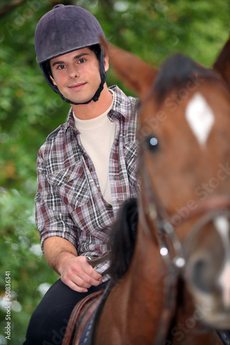 Photo: young man riding a horse young man riding a horse