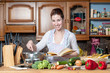 beautiful housewife cooking vegetables with cookbook