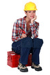 A female worker sitting on her toolbox.