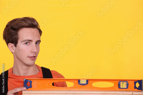 Photo: Man with spirit level on yellow background Man with spirit level on yellow background