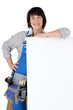 Photo: Female carpenter with a board left blank for your message Female carpenter with a board left blank for your message