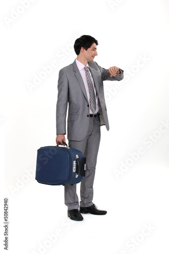 Photo: businessman with luggage consulting his watch businessman with luggage consulting his watch