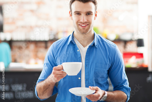 Photo: Man holding cup of coffee in cafe Man holding cup of coffee in cafe
