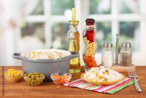 Photo: Risotto in gray pot on wooden table on bright background Risotto in gray pot on wooden table on bright background
