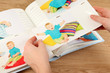 Photos in hands and photo album on wooden table