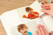 Photos in hands and photo album on wooden table
