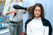 stylist drying woman hair in salon