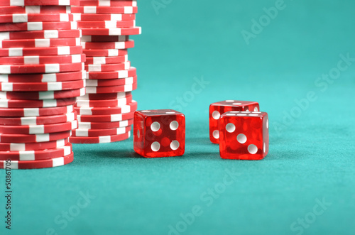 Photo: Red poker gambling chips on a green playing table Red poker gambling chips on a green playing table