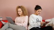 Two teenage friends sitting on couch with tablets