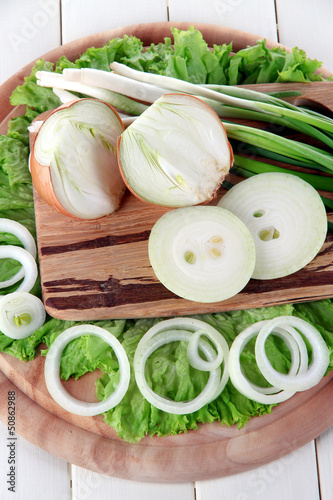 Photo: Composition with herbs and onions on wooden table Composition with herbs and onions on wooden table
