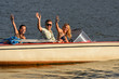 Young people waving from motorboat