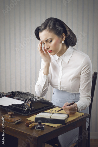 Photo: Worried woman sitting at desk in office Worried woman sitting at desk in office