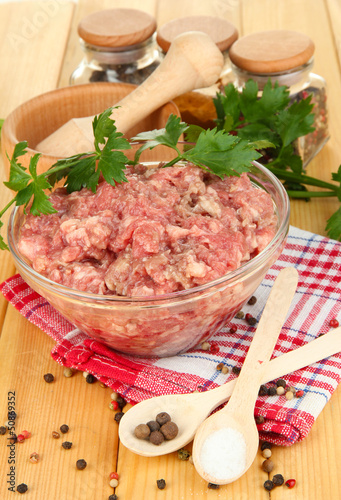 Photo: Bowl of raw ground meat with spices on wooden table Bowl of raw ground meat with spices on wooden table