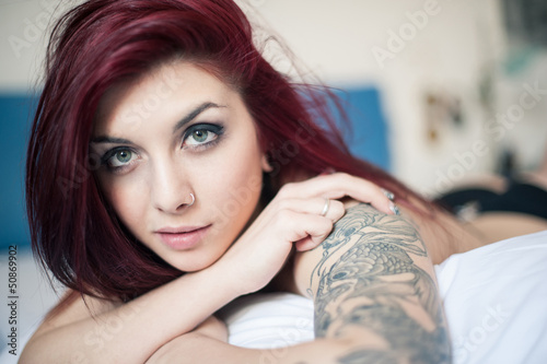 Photo: Sensual portrait of beautiful girl with tattoo lying on bed. Sensual portrait of beautiful girl with tattoo lying on bed.