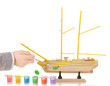Foto: Boy paints model sailing ship on white Boy paints model sailing ship on white