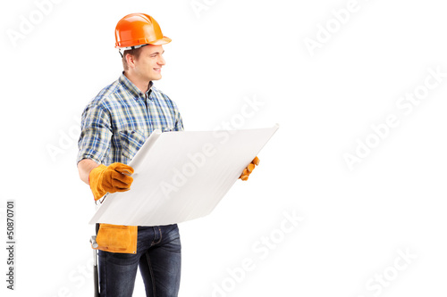 Photo: Male engineer with helmet and tool belt holding a blueprint Male engineer with helmet and tool belt holding a blueprint