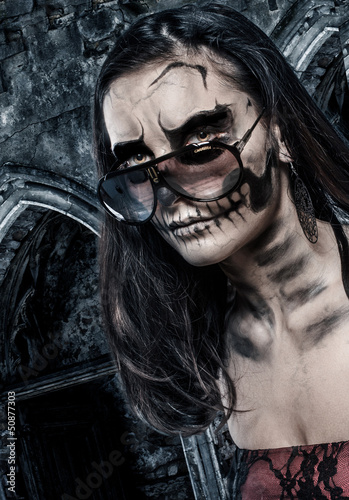 Photo: Skull faced girl on a castle background Skull faced girl on a castle background