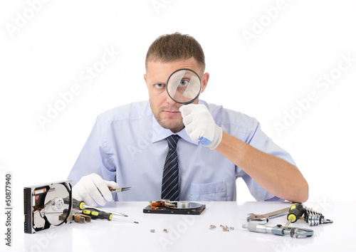 Photo: Hardware repairman with a magnifying glass on white Hardware repairman with a magnifying glass on white