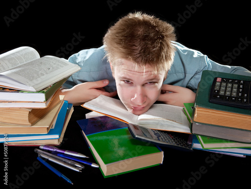 Photo: The teenager with a heap of textbooks. Was tired of homeworks The teenager with a heap of textbooks. Was tired of homeworks