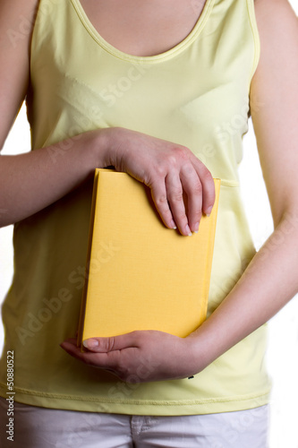 Photo: Woman holding a yellow book Woman holding a yellow book