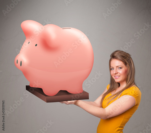 Photo: Young girl holding a huge savings piggy bank Young girl holding a huge savings piggy bank