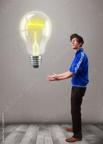Photo: Attractive man holding realistic 3d light bulb Attractive man holding realistic 3d light bulb