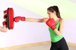 Young beautiful woman with boxing gloves at workout, at gym