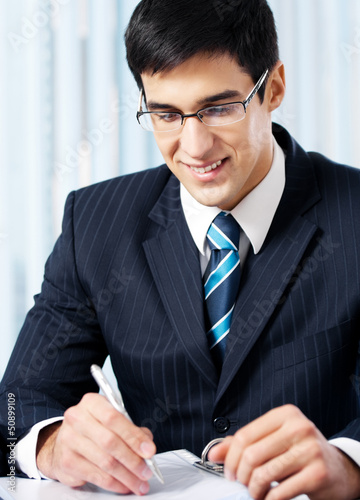 Photo: Portrait of writing smiling businessman working Portrait of writing smiling businessman working
