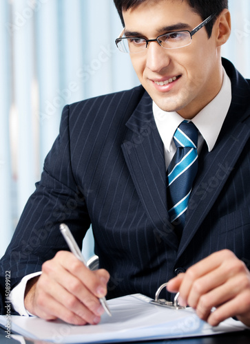 Photo: Portrait of writing smiling businessman working Portrait of writing smiling businessman working