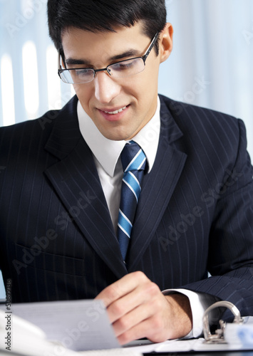 Photo: Successful businessman with documents at office Successful businessman with documents at office