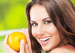 Young woman with orange, outdoors