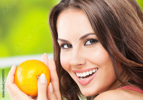 Photo: Young woman with orange, outdoors Young woman with orange, outdoors