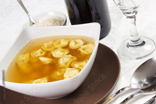 Photo: broth with ravioli over white tablecloth broth with ravioli over white tablecloth