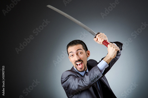 Photo: Angry businessman with sword in dark room Angry businessman with sword in dark room