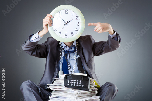 Photo: Man with clock and pile of papers Man with clock and pile of papers